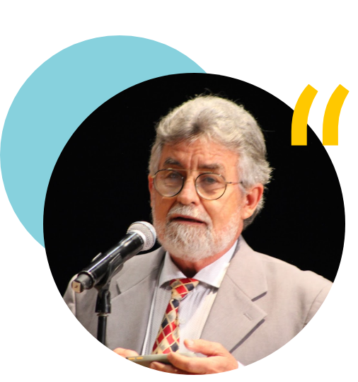 Foto do Coordenador do Censo da Psicologia Brasileira, Antonio Virgílio: homem branco, cabelos grisalhos, óculos arredondados, de terno cinza claro e gravata gradriculada, falando em um microfone de um evento